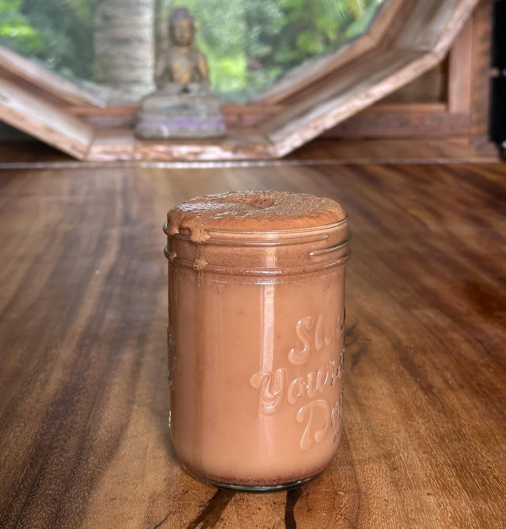 Jar of chocolate shake on a wooden surface with a blurred background